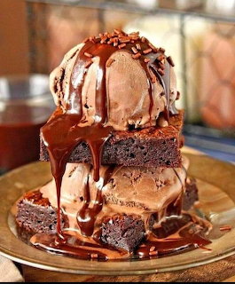 Stack of chocolate brownies with vanilla ice cream scoops and chocolate caramel drizzle on gold plate