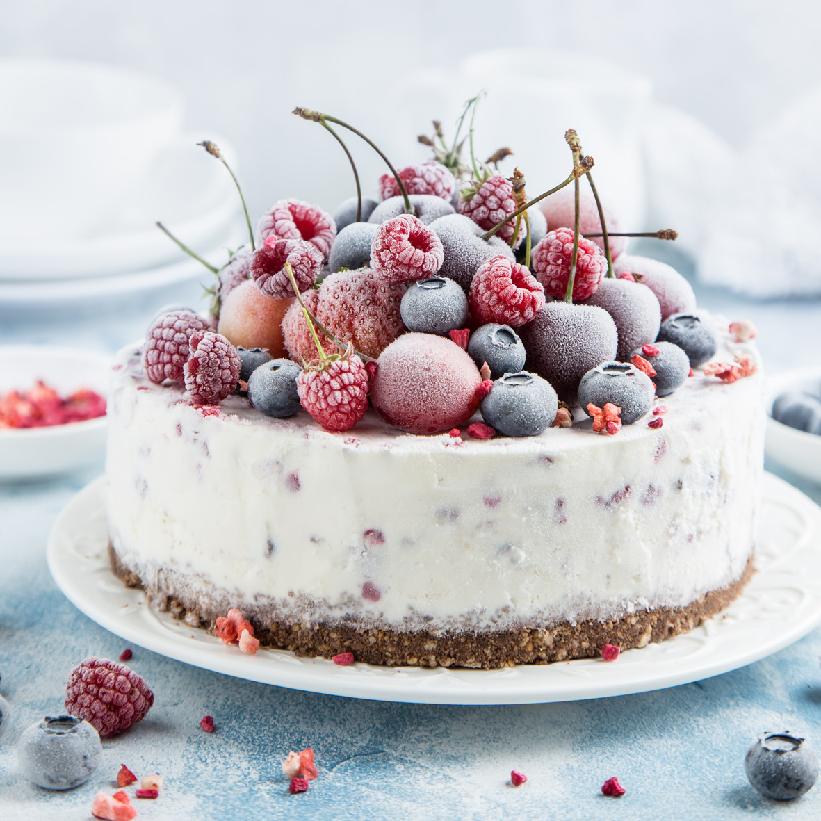 Round ice cream cake decorated with sugar-frosted mixed berries including raspberries, blueberries, and cherries
