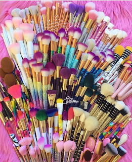 Collection of makeup brushes with vibrant multicolored handles spread out on pink fur background