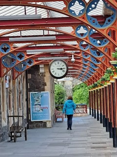 Victorian railway station platform with ornate red iron arches and clock