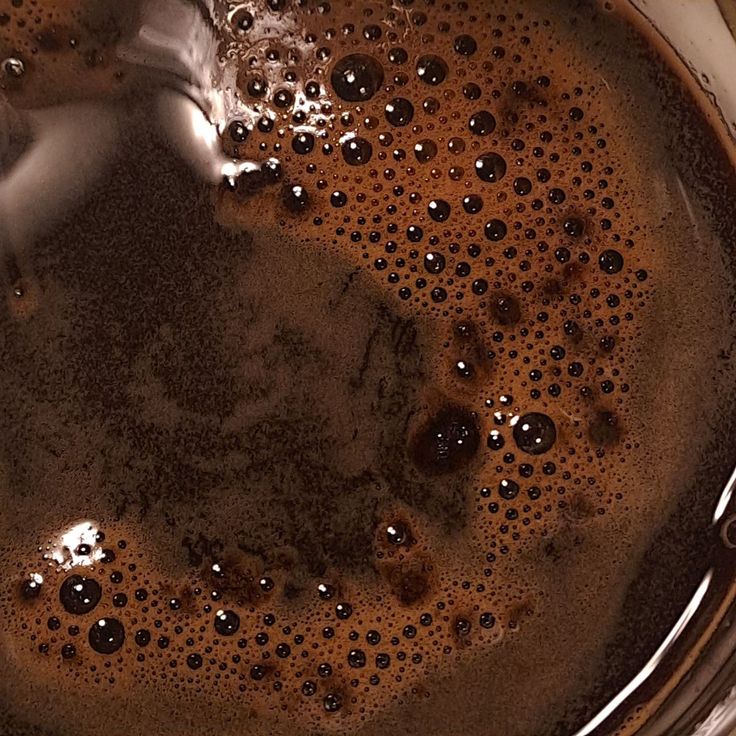 Overhead view of black coffee with brown crema and bubble patterns on surface