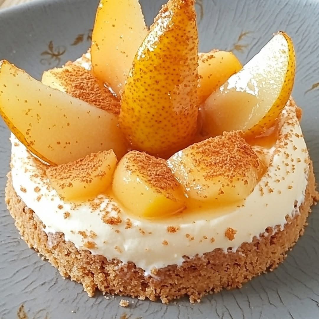 Round dessert with white cream, caramelized pear slices, and speculoos crumb crust on gray plate
