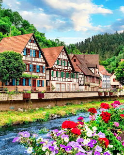 Colorful half-timbered buildings beside a river with flower beds in Schiltach, Germany