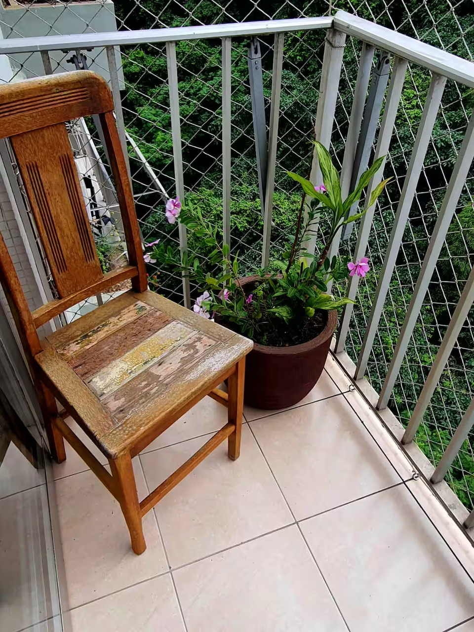 Wooden chair on balcony with white lattice railing and potted plants