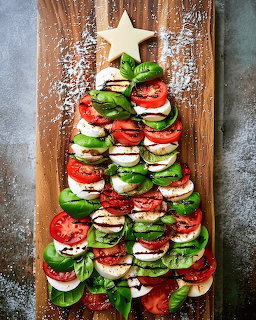 Caprese salad ingredients arranged as a Christmas tree on wooden cutting board