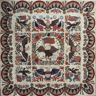 Patriotic quilt with eagles, flags, and floral motifs in red, white, and blue