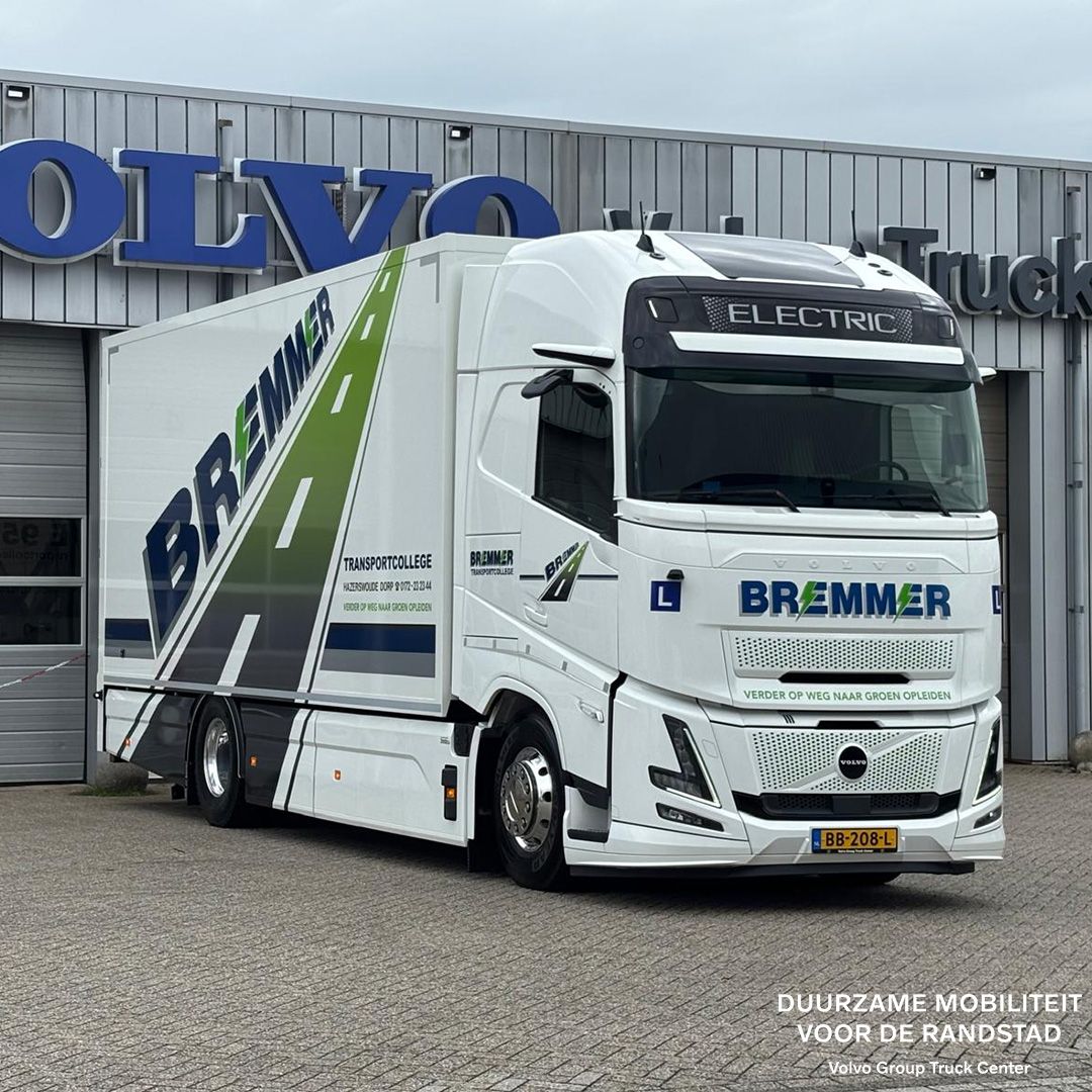 White electric truck with green stripes parked at industrial facility