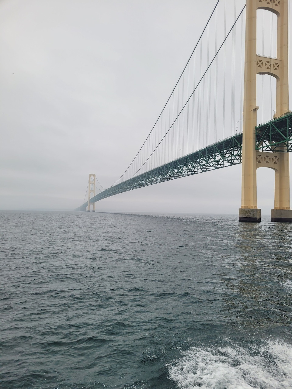 Mackinac Bridge over water at sunset with reflections on calm straits