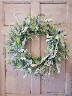 Green and cream wreath with lamb's ear and eucalyptus on a rustic beige wooden door