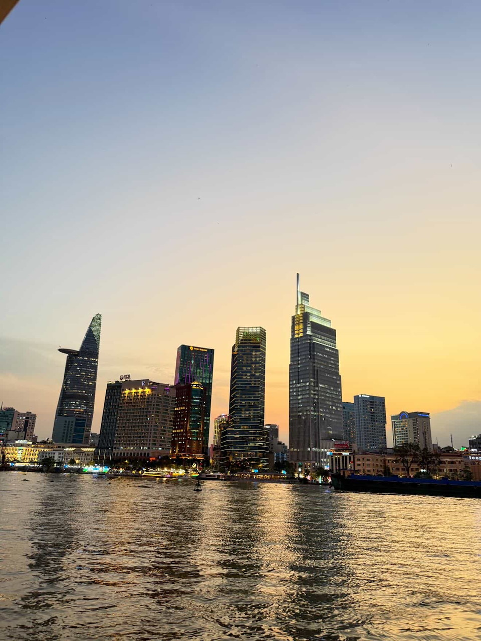 Ho Chi Minh City skyline at sunset with skyscrapers reflected on the Saigon River