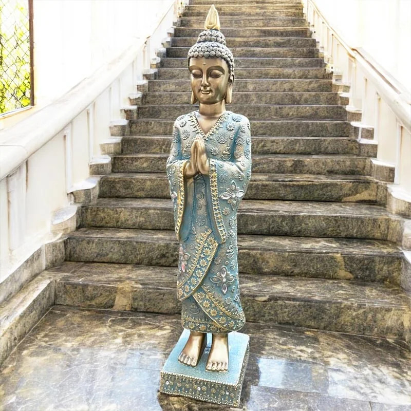 Standing Buddha statue in ornate robes at the bottom of a stone staircase
