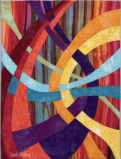 Abstract quilt with curved colorful fabric strips in geometric pattern on striped background