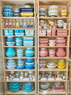 Shelves filled with organized vintage Pyrex bowls and dishes in blue, pink, yellow and patterned designs