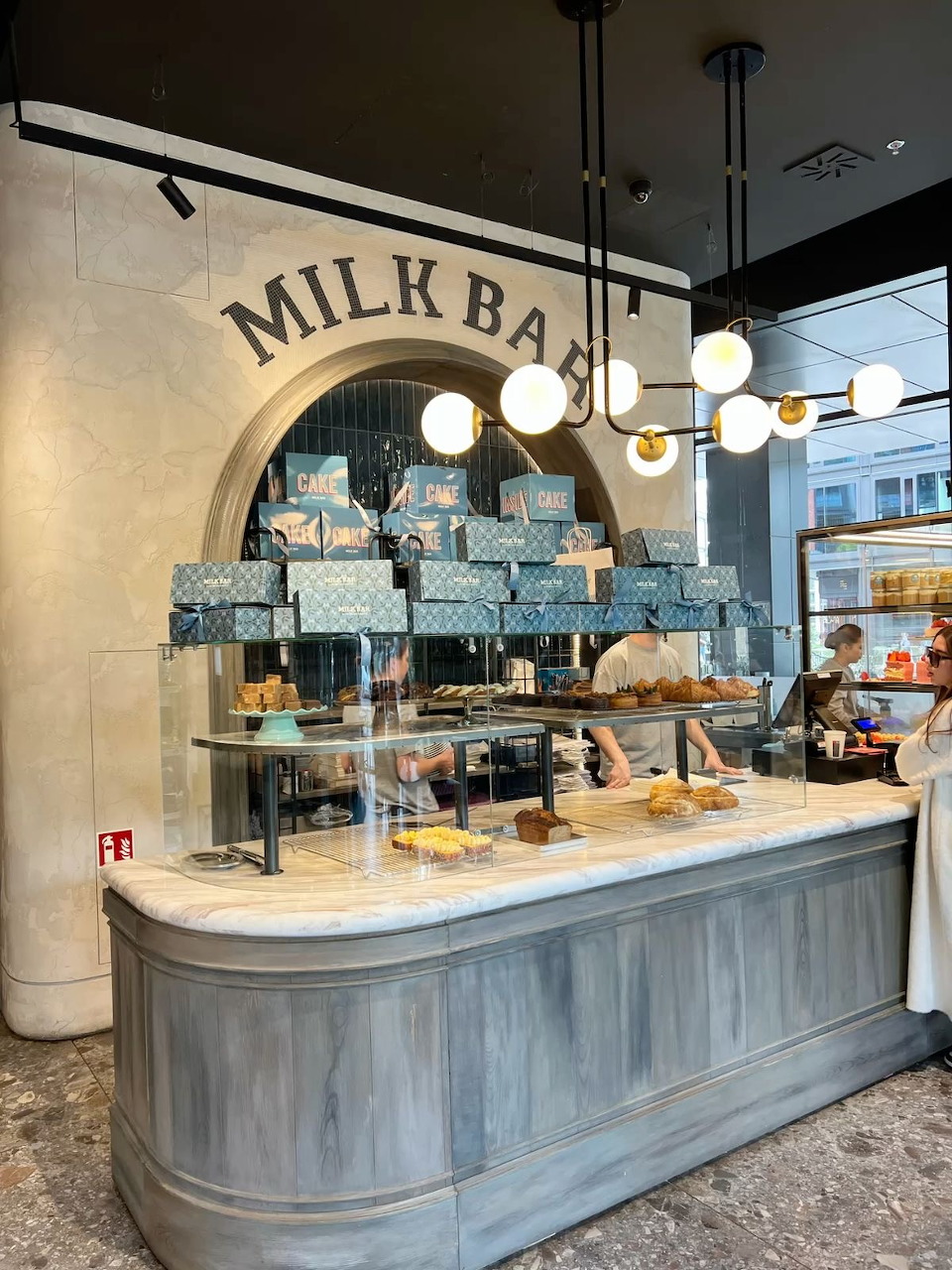 Modern bakery counter with pastries, display cases, and hanging globe lights.