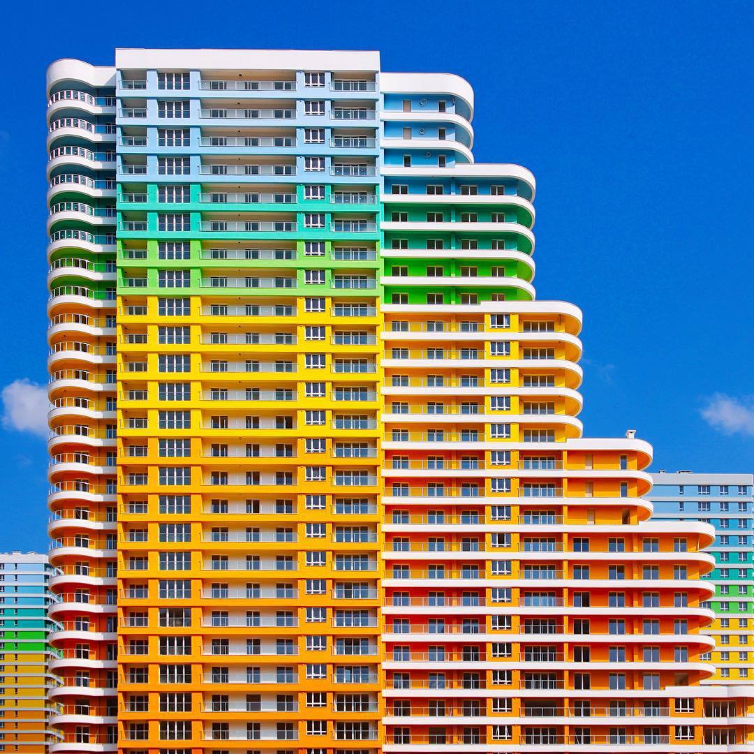 Multi-story apartment buildings with rainbow-colored horizontal stripes and balconies in geometric arrangement