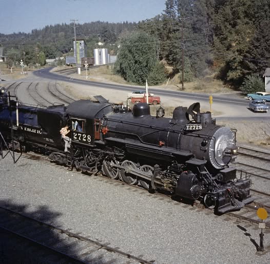 Black steam locomotive 5228 on railroad tracks in a rail yard