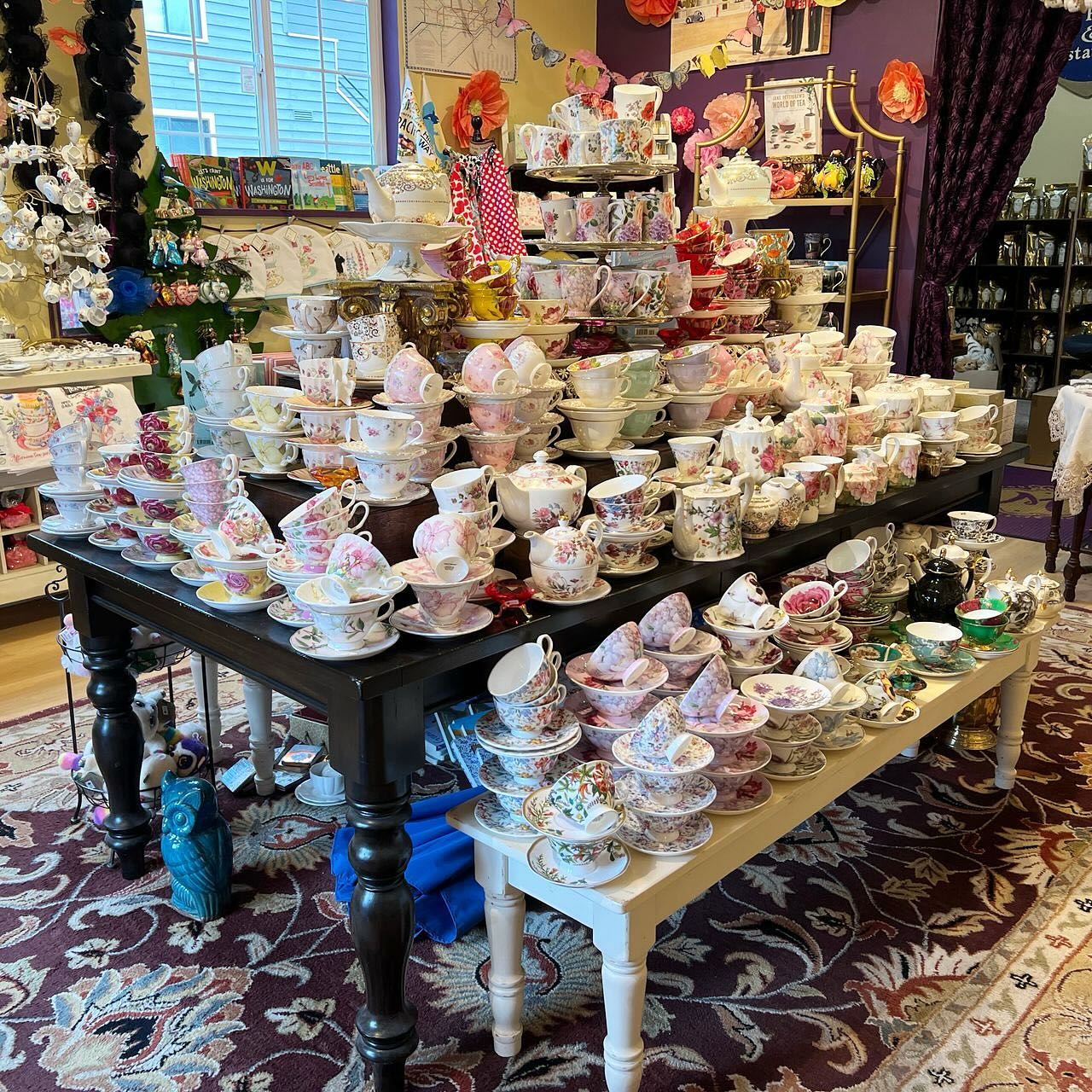 Floral china teacups, plates, and serving dishes displayed on tables inside a shop