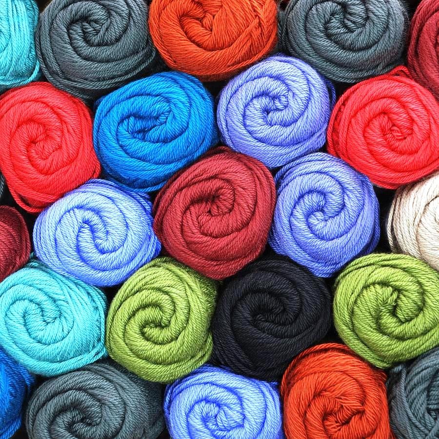 Colorful rolled yarn skeins arranged in rows showing various bright colors