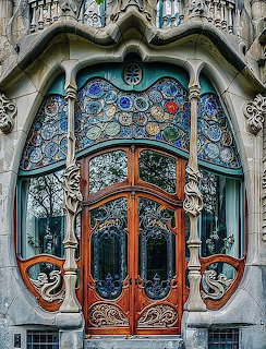 Ornate Art Nouveau entrance door with stained glass and dragon-shaped stone carvings at Casa Batlló Barcelona