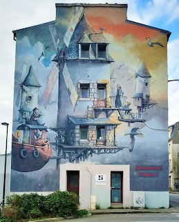 Colorful abstract mural painted on multi-story building exterior with birds and nautical themes
