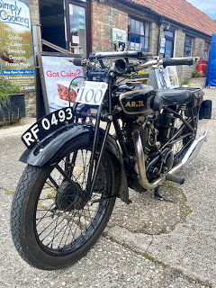 Vintage black Ariel motorcycle with registration RF 0493 parked outside brick building