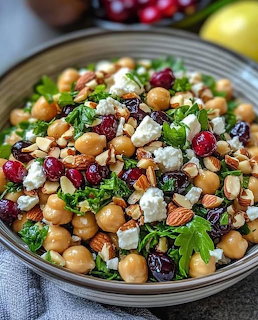 Bowl of chickpea salad with feta cheese, cranberries, almonds, and grens in a ceramic bowl