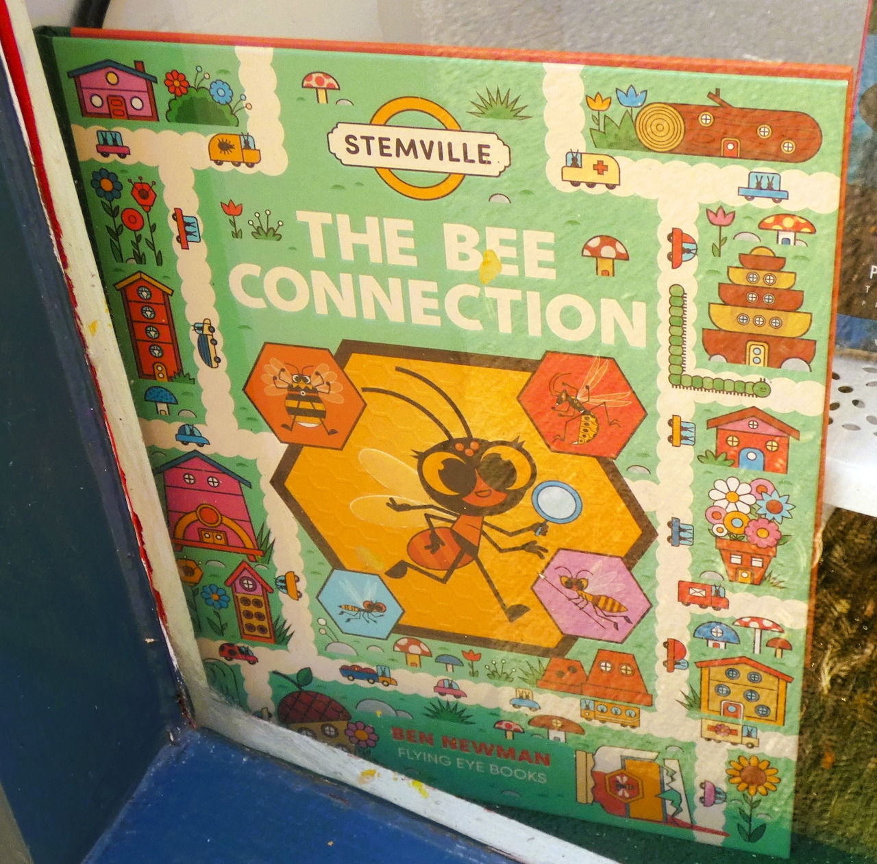 Colorful book cover for The Bee Connection with a large illustrated bee and honeycomb shapes