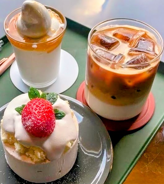 Two iced coffee drinks and a small strawberry cake on a tray