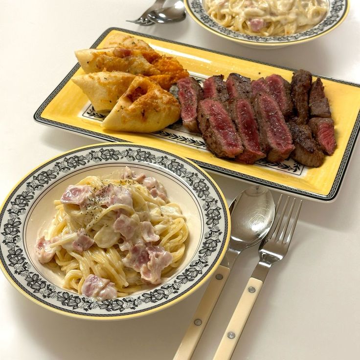 Overhead view of Korean barbecue beef, dumplings, pasta with ham, and noodle soup on white background