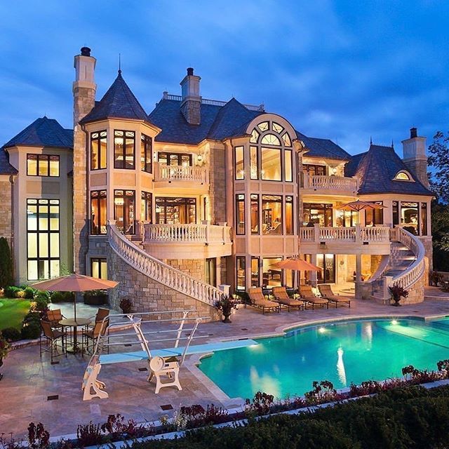 Luxury mansion with illuminated windows and swimming pool at dusk