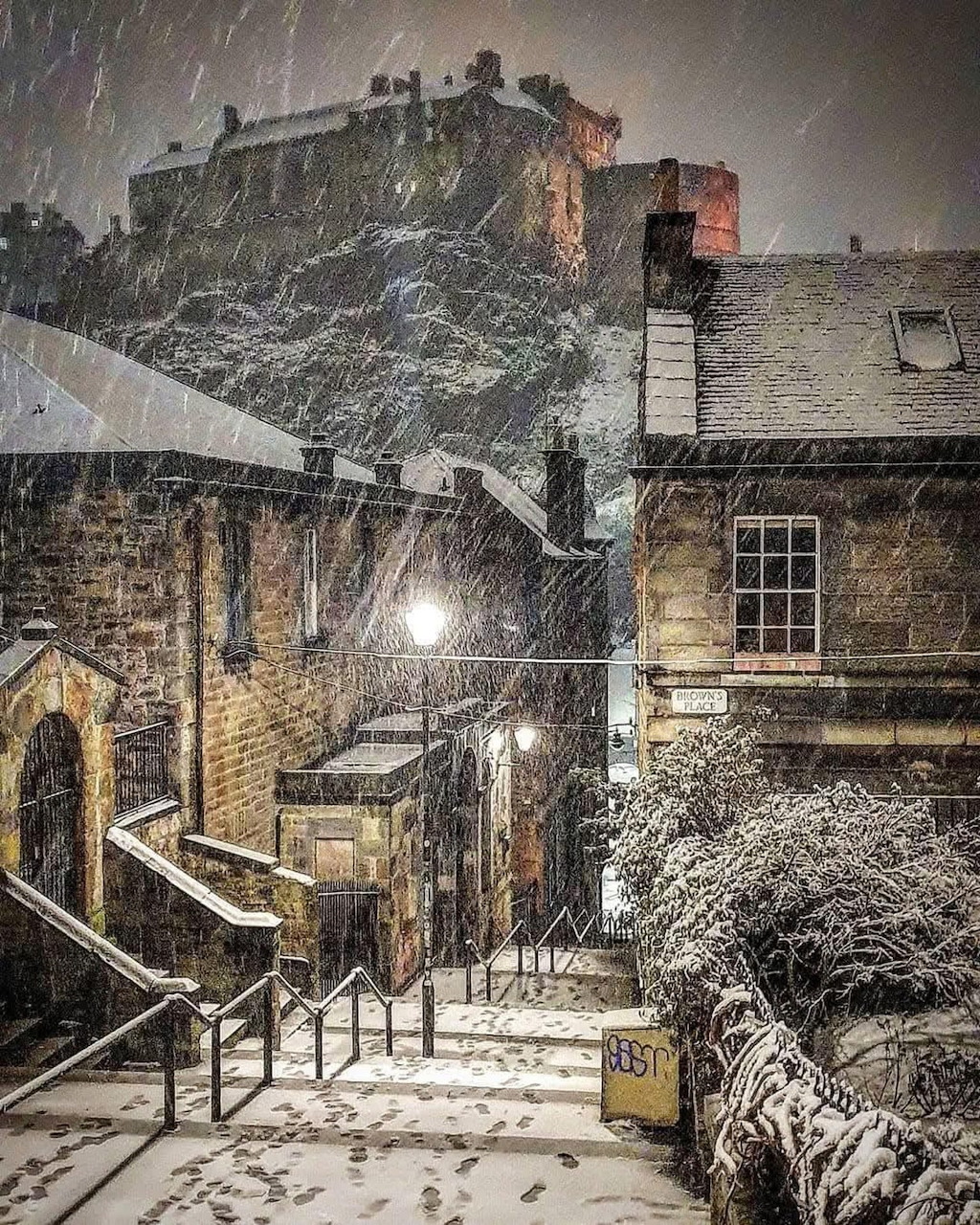 Edinburgh Castle on a snowy winter day with stone steps leading up, buildings covered in snow