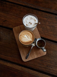 Top-down view of three coffee drinks on a wooden board on a dark wooden table.