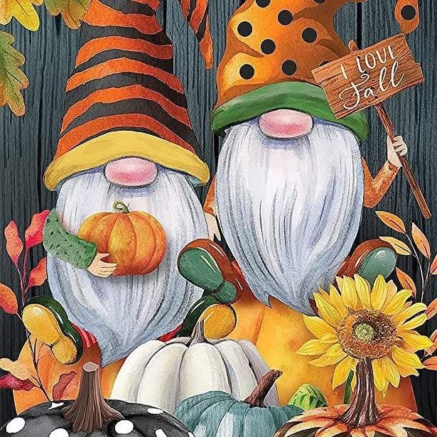Two decorative gnomes with white beards wearing striped hats, holding pumpkins and sunflower with fall themed background