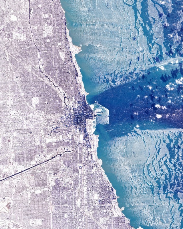 Satellite image of frozen Lake Michigan with ice patterns next to Chicago cityscape in winter