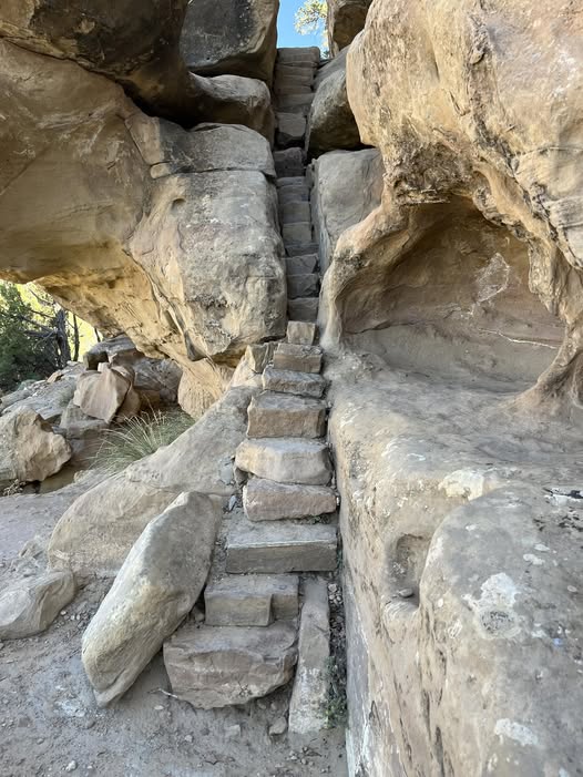 Ancient stone staircase rising through a narrow passage between weathered sandstone walls.