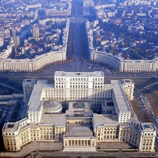 Aerial view of the Palace of Parliament in Bucharest with a long boulevard and surrounding cityscape