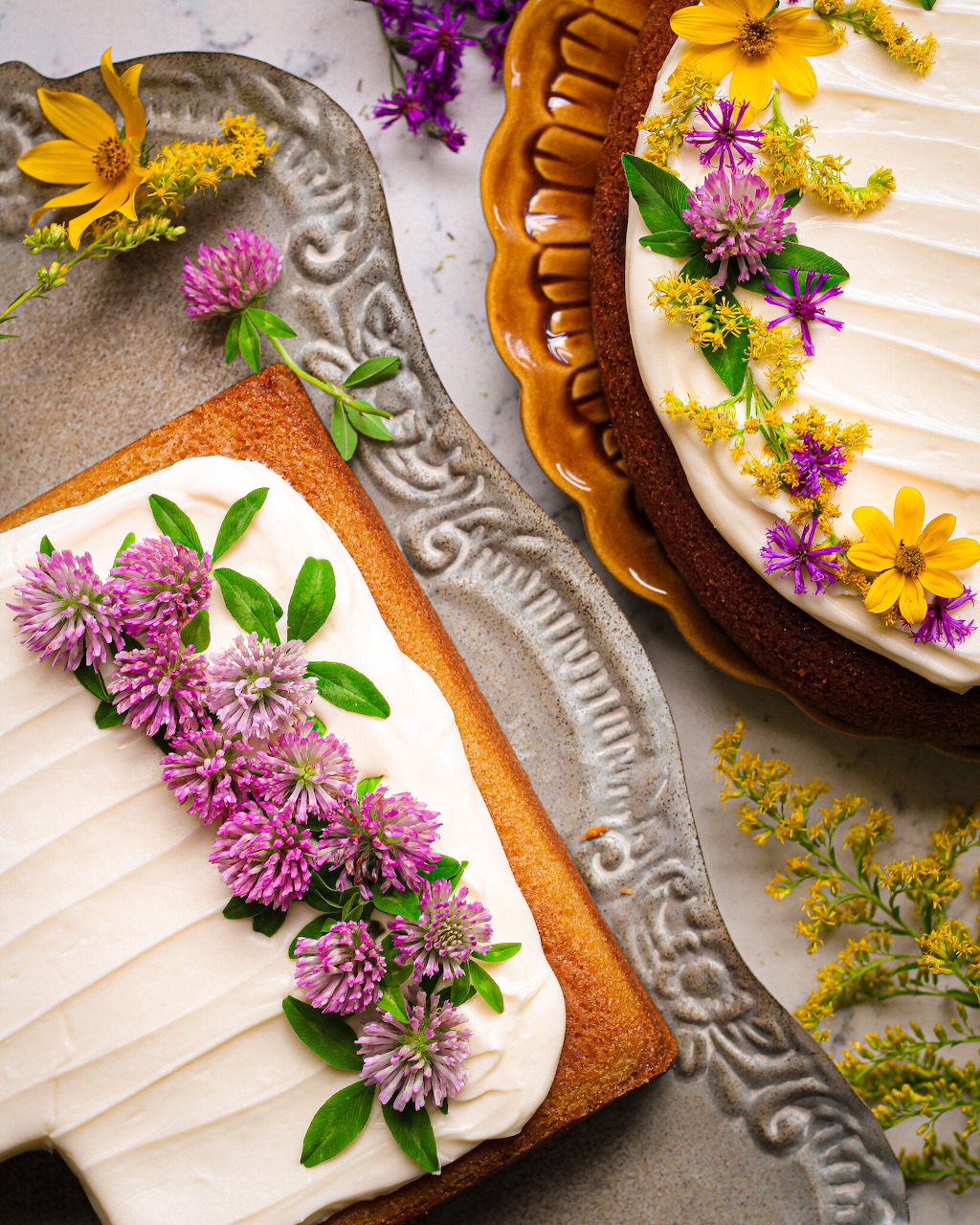 Two rectangular sheet cakes decorated with colorful fresh flowers on white frosting