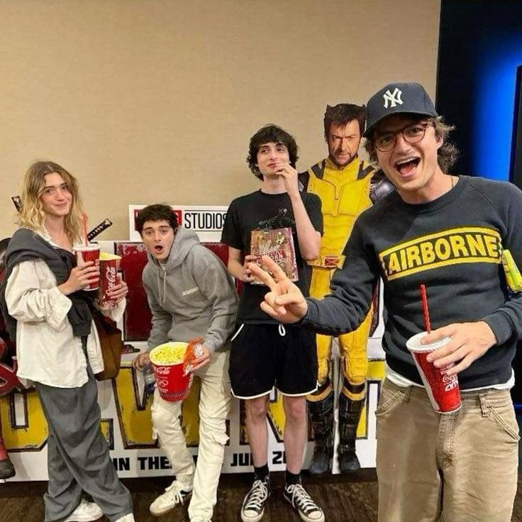 Stranger Things cast members posing together in casual clothing holding red cups