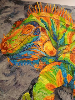 Colorful quilted fabric lizard with intricate stitching and beadwork in vibrant orange, green, blue and yellow patterns