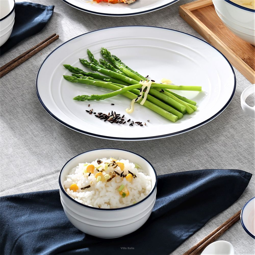 Fresh asparagus spears tied on a white plate with bowls of rice on a gray table