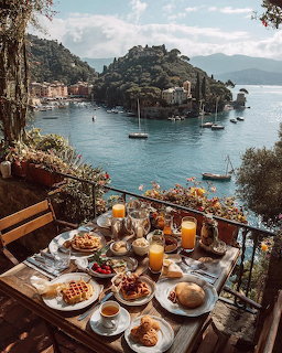 Breakfast spread on terace overlooking Italian coastal town and bay with sailboats