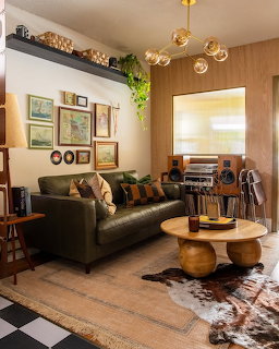 Cozy retro living room with green leather sofa, round coffee table, gallery wall, and vintage stereo