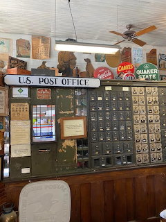 Historic post office interior with brass mailbox wall, wooden counter, vintage signs and ceiling fan