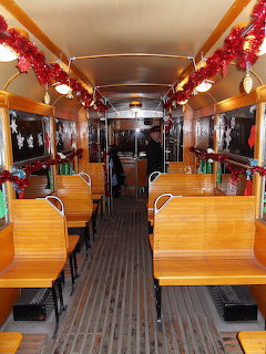Interior of vintage tram with wooden seats and decorative red garlands along the ceiling