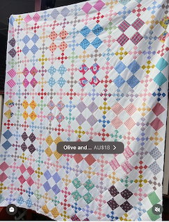 Colorful patchwork quilt with diamond pattern in various bright colors on white fabric