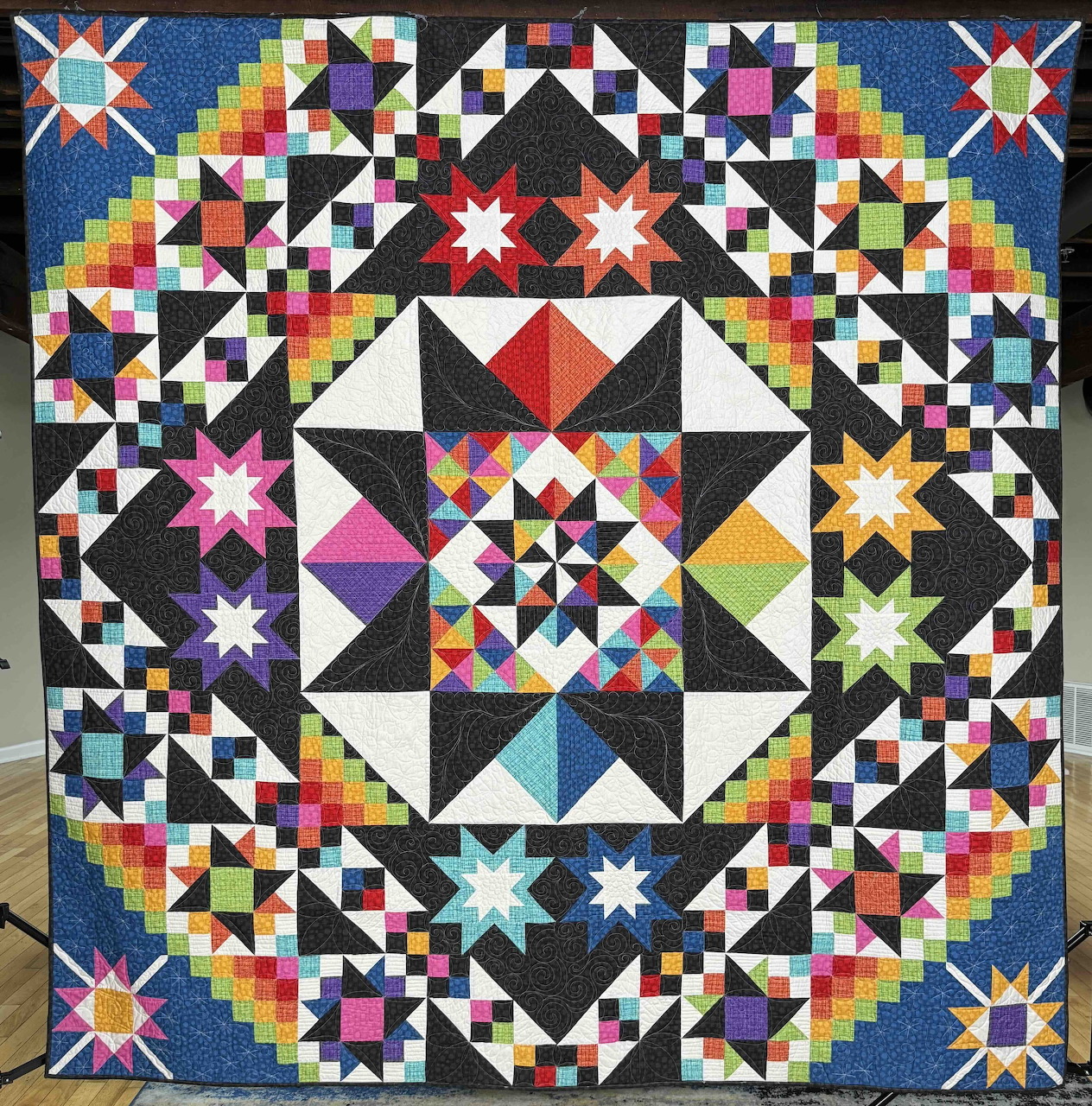 Colorful geometric quilt with star shapes, triangles, and rainbow patchwork in a symmetrical design