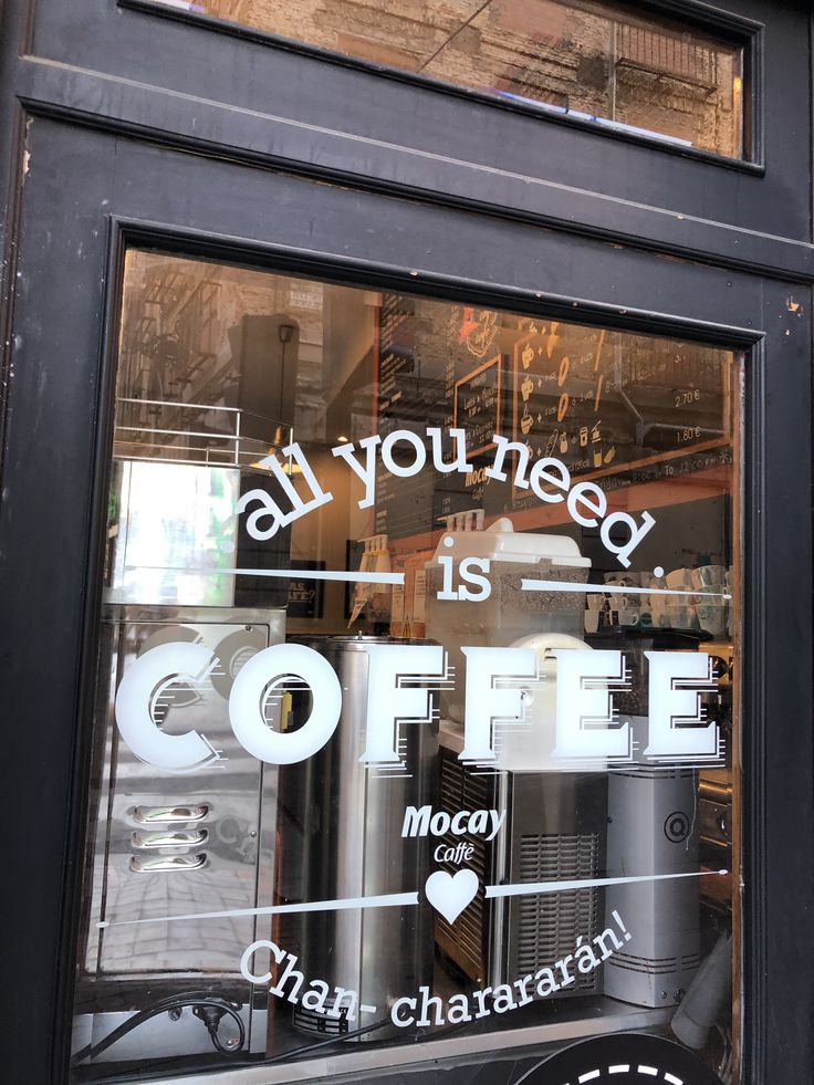 Café window with 'All You Need Is Coffee' lettering and Mocay Café sign