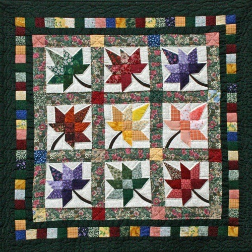 Patchwork quilt with nine colorful star pattern blocks in autumn hues arranged in grid with decorative border