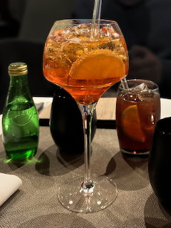 Aperol Spritz cocktail in a wine glass with orange slice on a restaurant table with other drinks