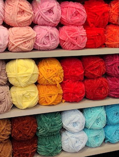 Shelves of colorful yarn balls arranged in rows by color